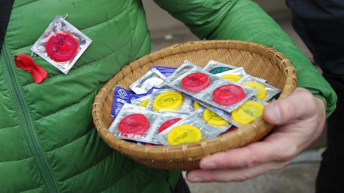 Una mujer sujetando una cesta con preservativos (condones), en la concentración silenciosa convocada por la Asociación Sare y la Comisión Ciudadana Anti-Sida de Navarra