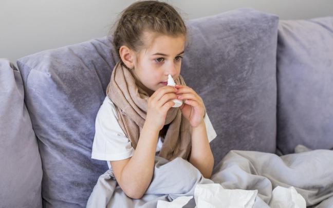 Una niña usando un spray nasal.