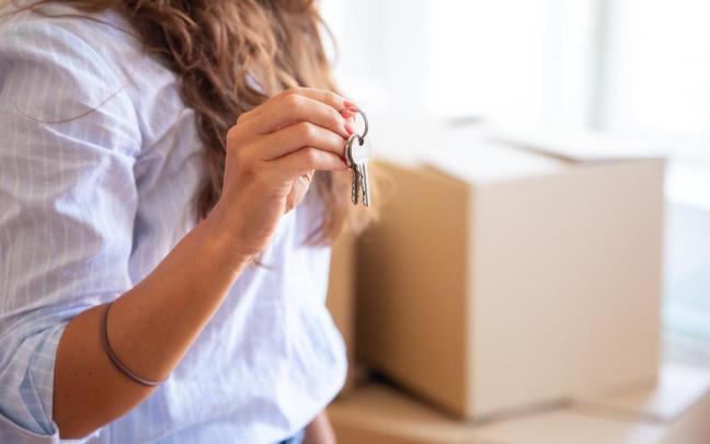 Una mujer muestra las llaves de su nueva vivienda.