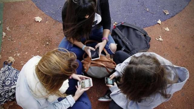 Un grupo de menores usando sus teléfonos móviles en un parque.