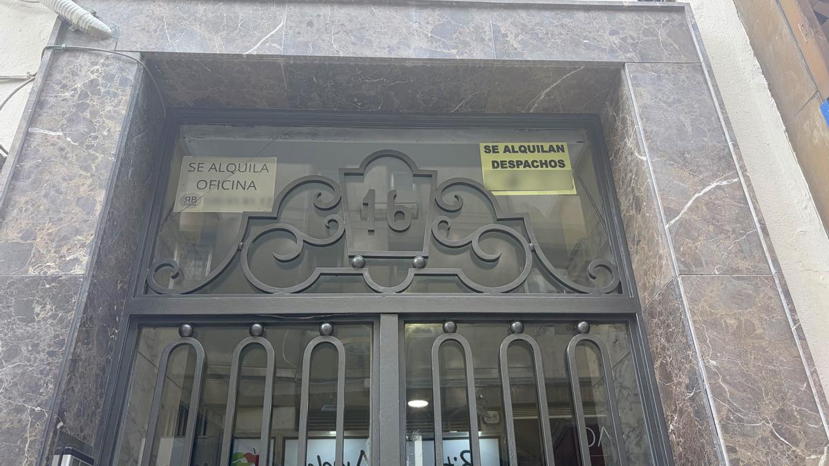 Fachada de un potal con carteles de alquiler.