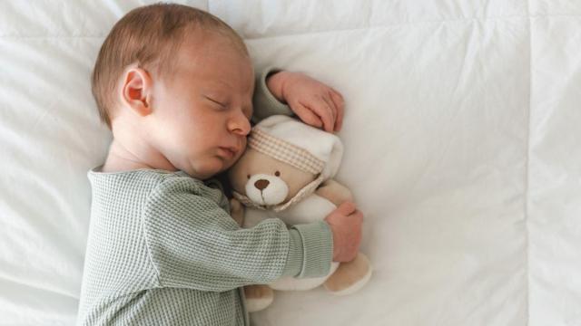 Bebé dormido abrazada a un muñeco.