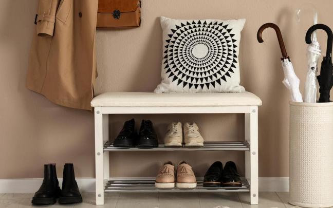 Paragüero colocado junto a un banco zapatero en un recibidor.