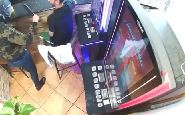 El atracador, con el machete entre dos clientes del bar.