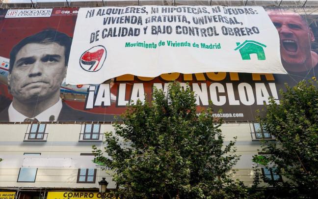 La lona desplegada por activistas antidesahucios por encima de la de Desokupa.