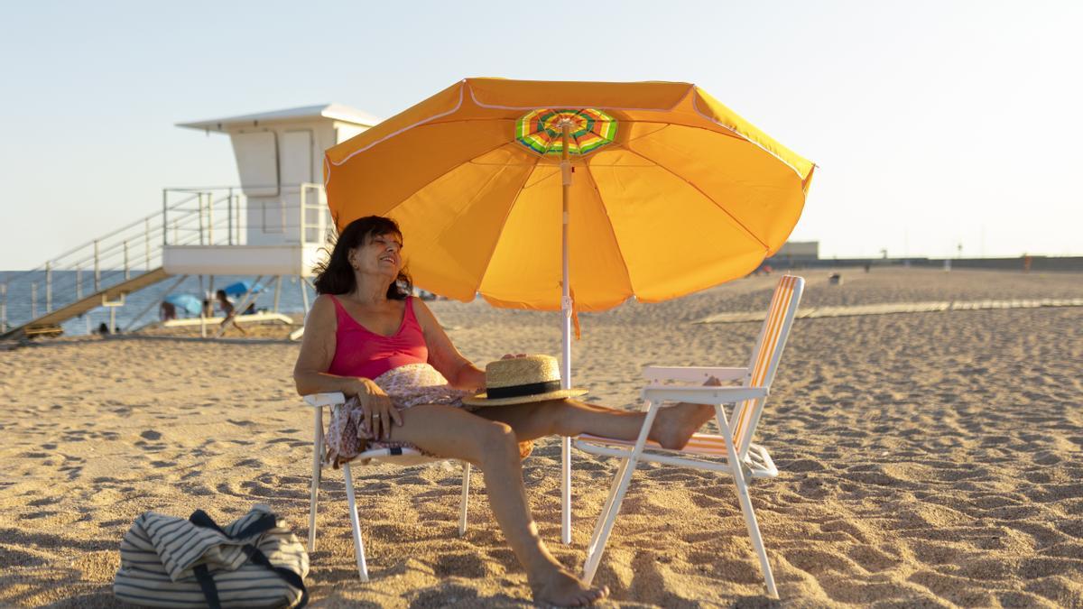 Una persona con sombrilla en la playa.