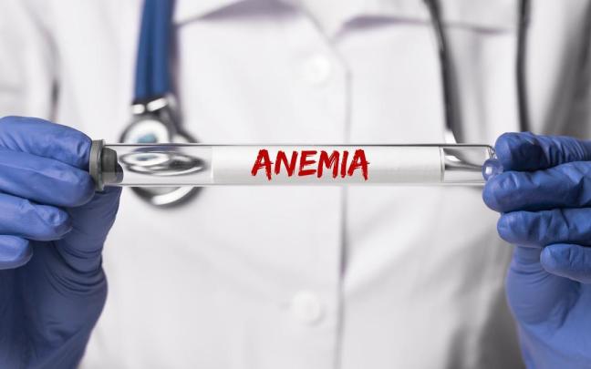 Un médico sujeta en sus manos un tubo de ensayo con la palabra 'anemia'.