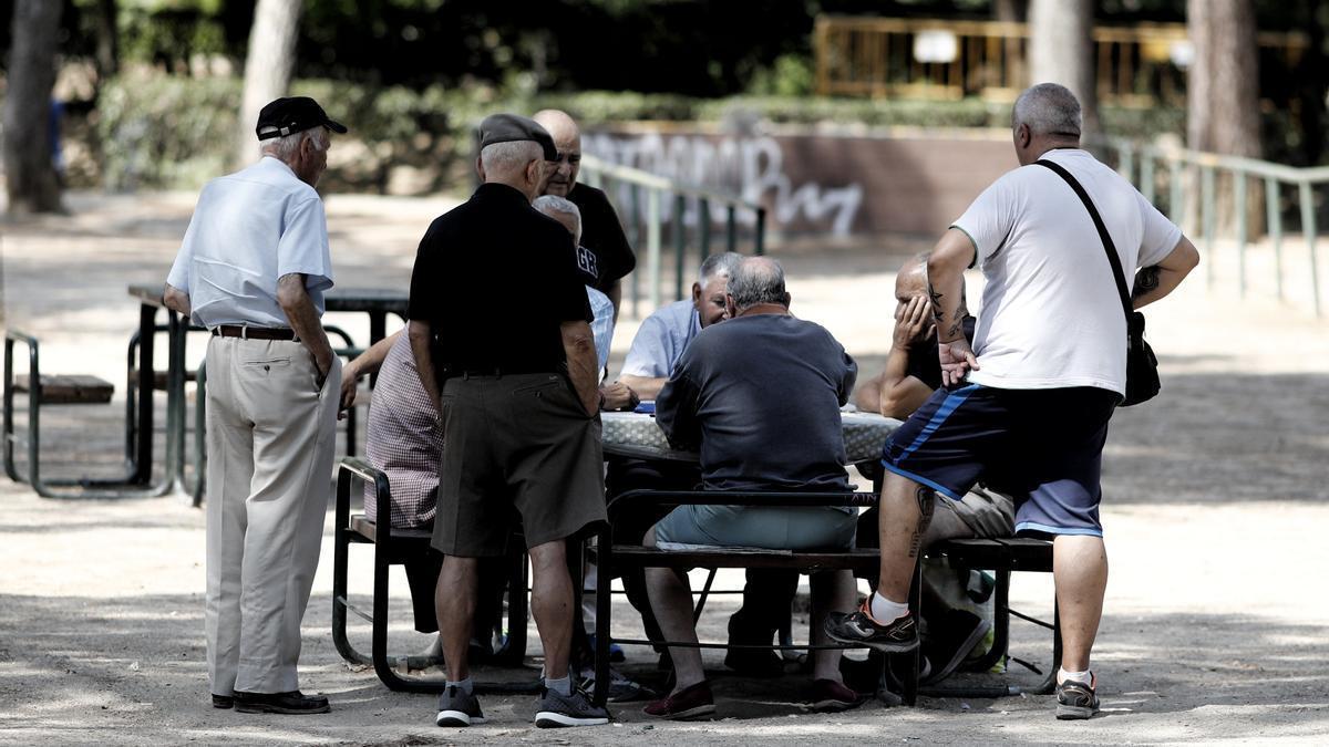 Varios pensionistas juegan al dominó en un parque.