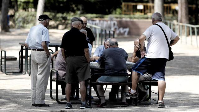 Varios pensionistas juegan al dominó en un parque.