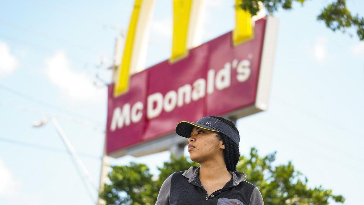 Una empleada ante un cartel de la cadena de comida rápida.