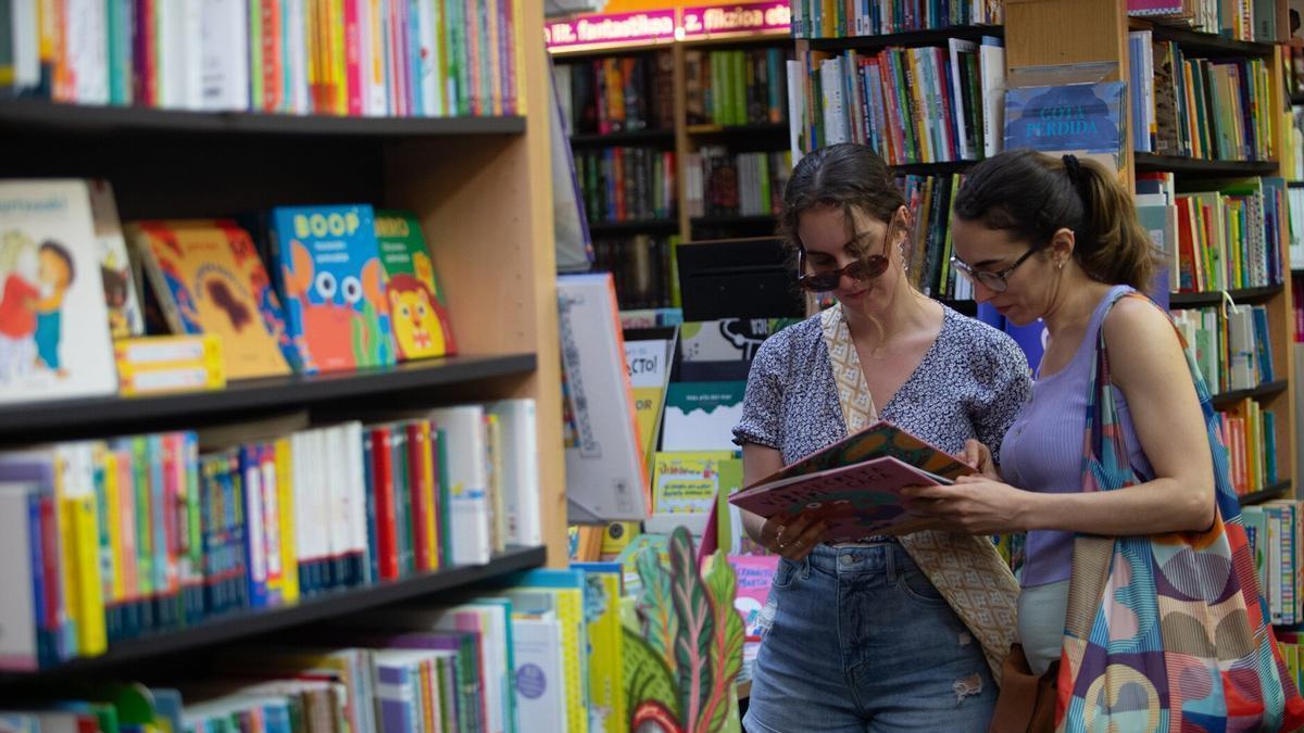 Dos jóvenes miran libros en una librería.