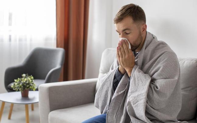 Hombre con gripe se suena la nariz en el sofá mientras se tapa con una manta / Freepik Hombre con gripe se suena la nariz en el sofá mientras se tapa con una manta