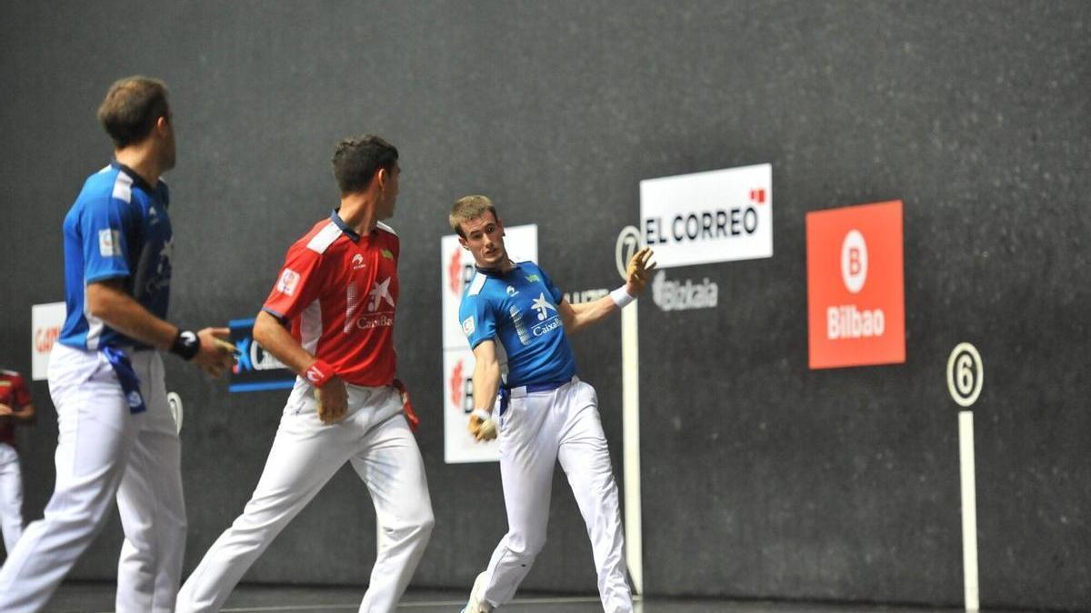 Mariezkurrena golpea la pelota en presencia de Urrutikoetxea y Peña.