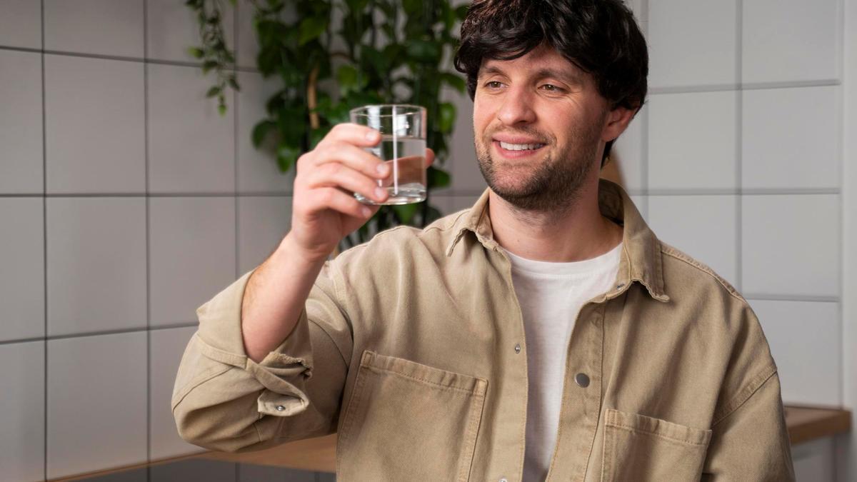 Un hombre toma un vaso de agua antes de desayunar.