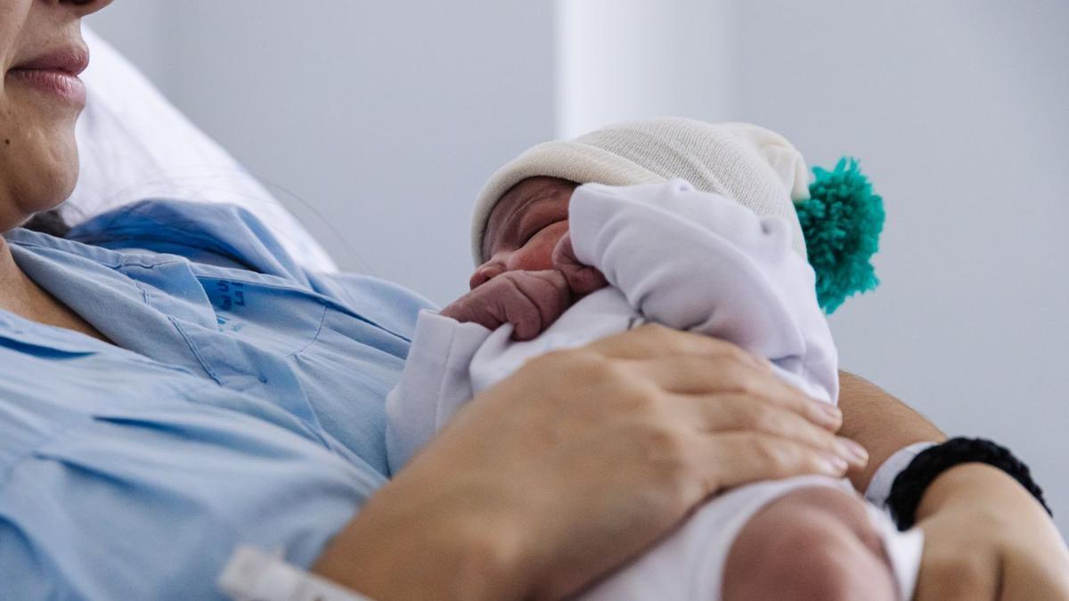 Una mujer sostiene a su hijo recién nacido en 2023, el peor año en nacimientos en más de medio siglo.