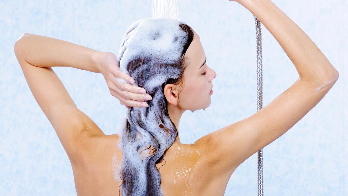 Mujer sacándose el champú en la ducha