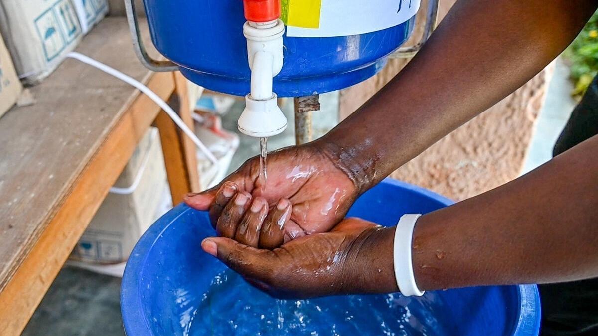 Una persona se lava las manos en un dispensador con una solución clorada al 0.05%, instalada en una comunidad de RDC para fomentar la higiene de manos y prevenir el cólera.