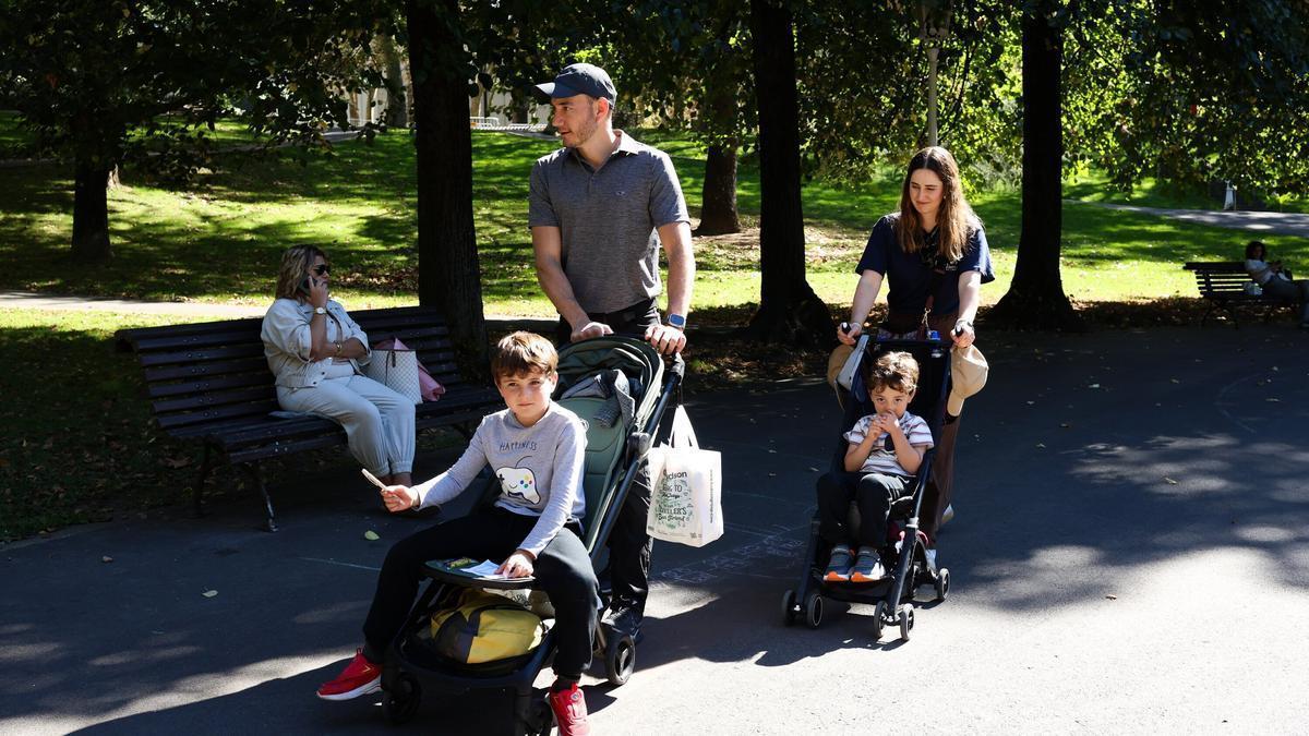 Padres pasean con sus hijos en el parque.