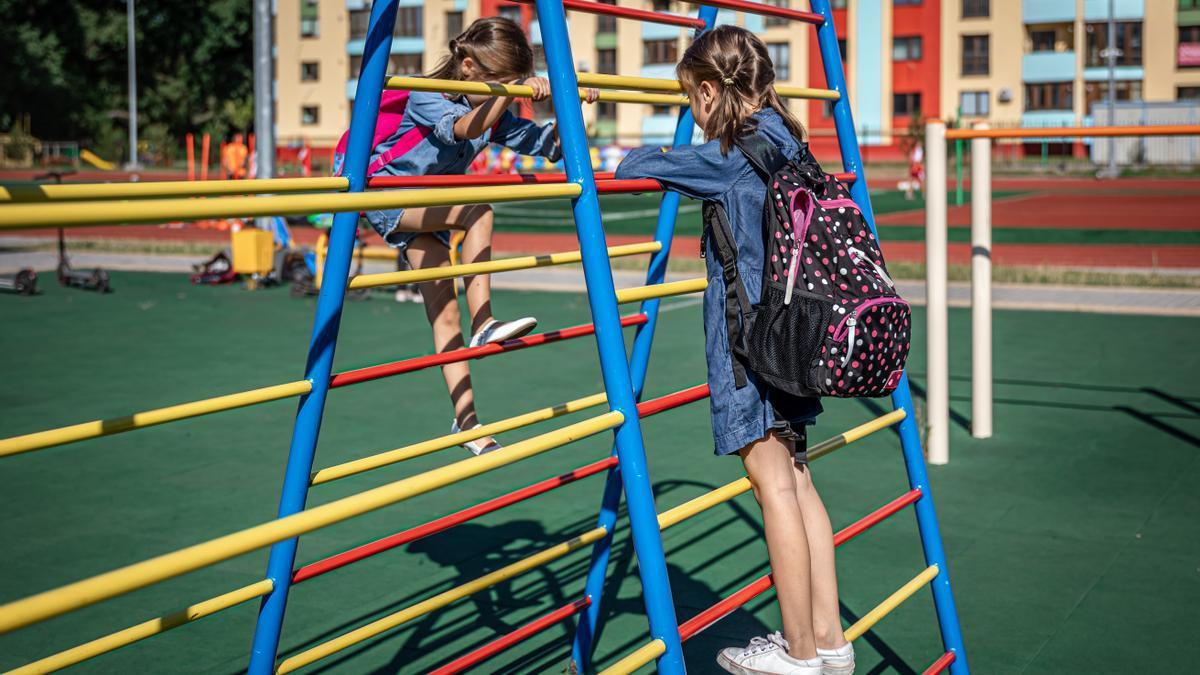 Dos niñas jugando en el patio de un colegio.