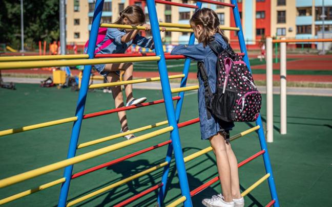 Dos niñas jugando en el patio de un colegio.