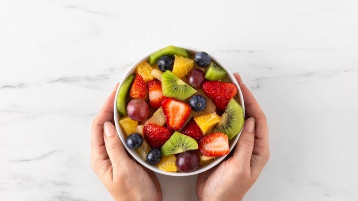 Manos sostienen un bowl con frutas variadas