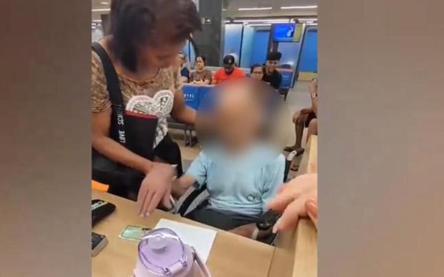 La mujer sujeta la cabeza del finado e intenta que firme el documento para que se le conceda el préstamo. / Twitter La mujer sujeta la cabeza del finado e intenta que firme el documento para que se le conceda el préstamo.