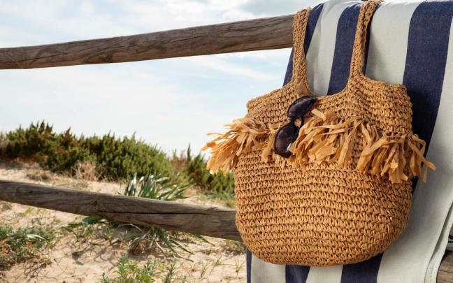 Toalla y bolso colgados en una barandilla de madera en la playa. Toalla y bolso colgados en una barandilla de madera en la playa.
