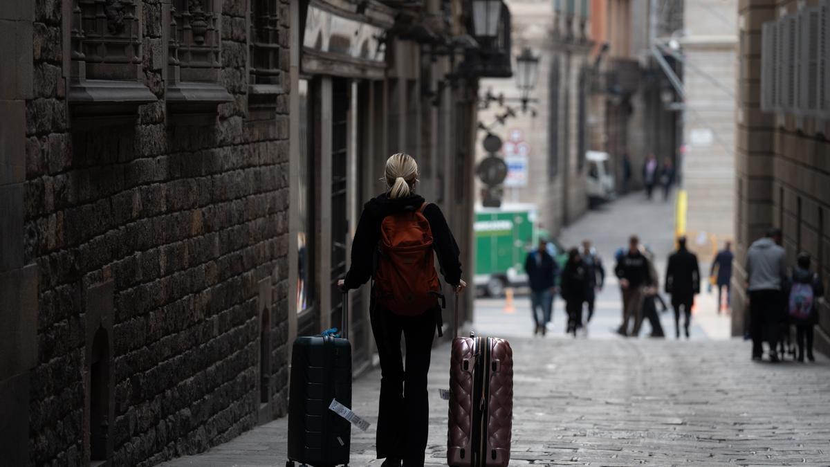 Una persona con dos maletas, por una calle de Barcelona.