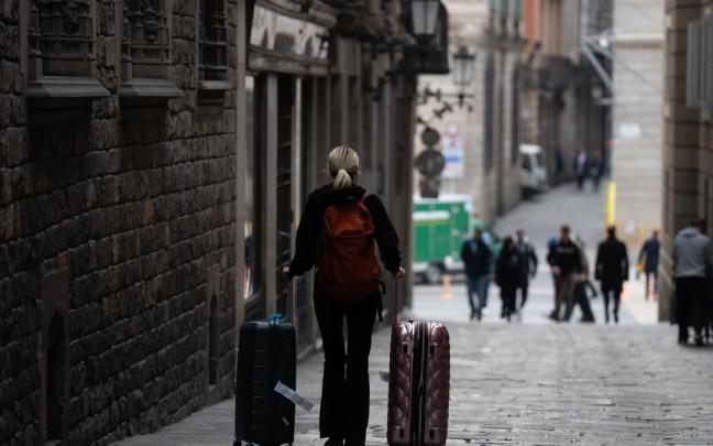 Una persona con dos maletas, por una calle de Barcelona.