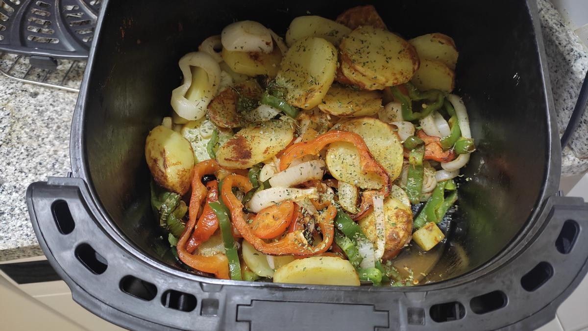 Las patatas y la verdura, a medio cocinado dentro de la cesta de la freidora de aire.
