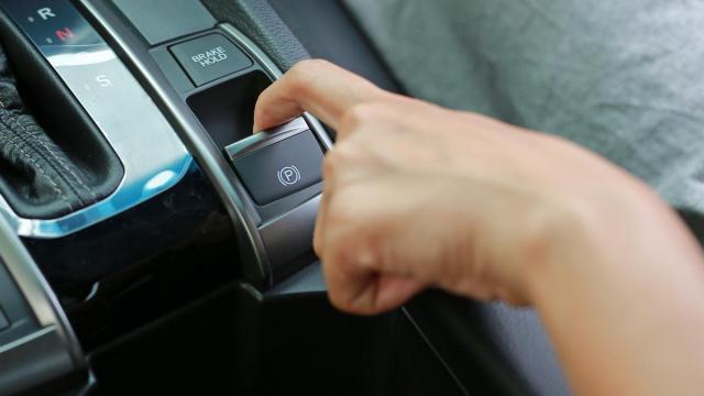 Una persona acciona el freno de mano eléctrico de su coche.