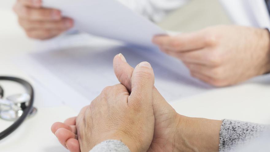 Un médico de cabecera mirando la historia de un paciente en consulta.