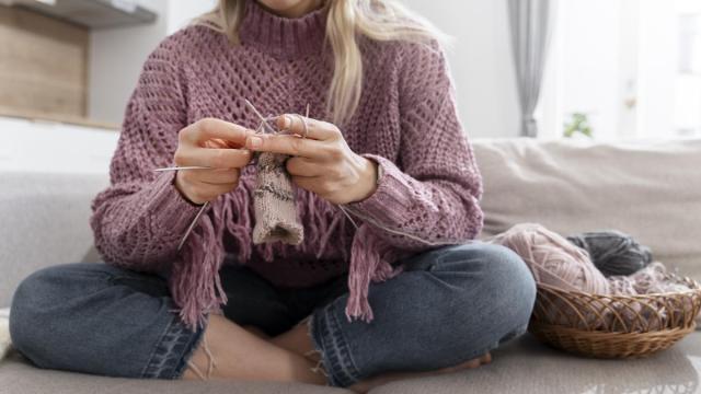 Una chica con varias agujas tejiendo con lana