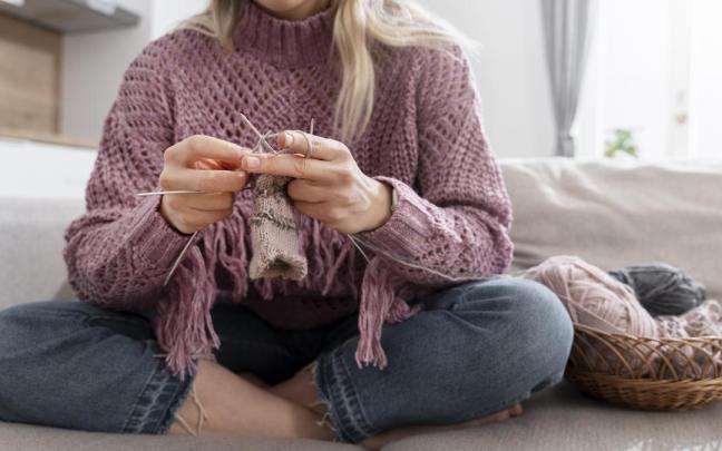 Una chica con varias agujas tejiendo con lana