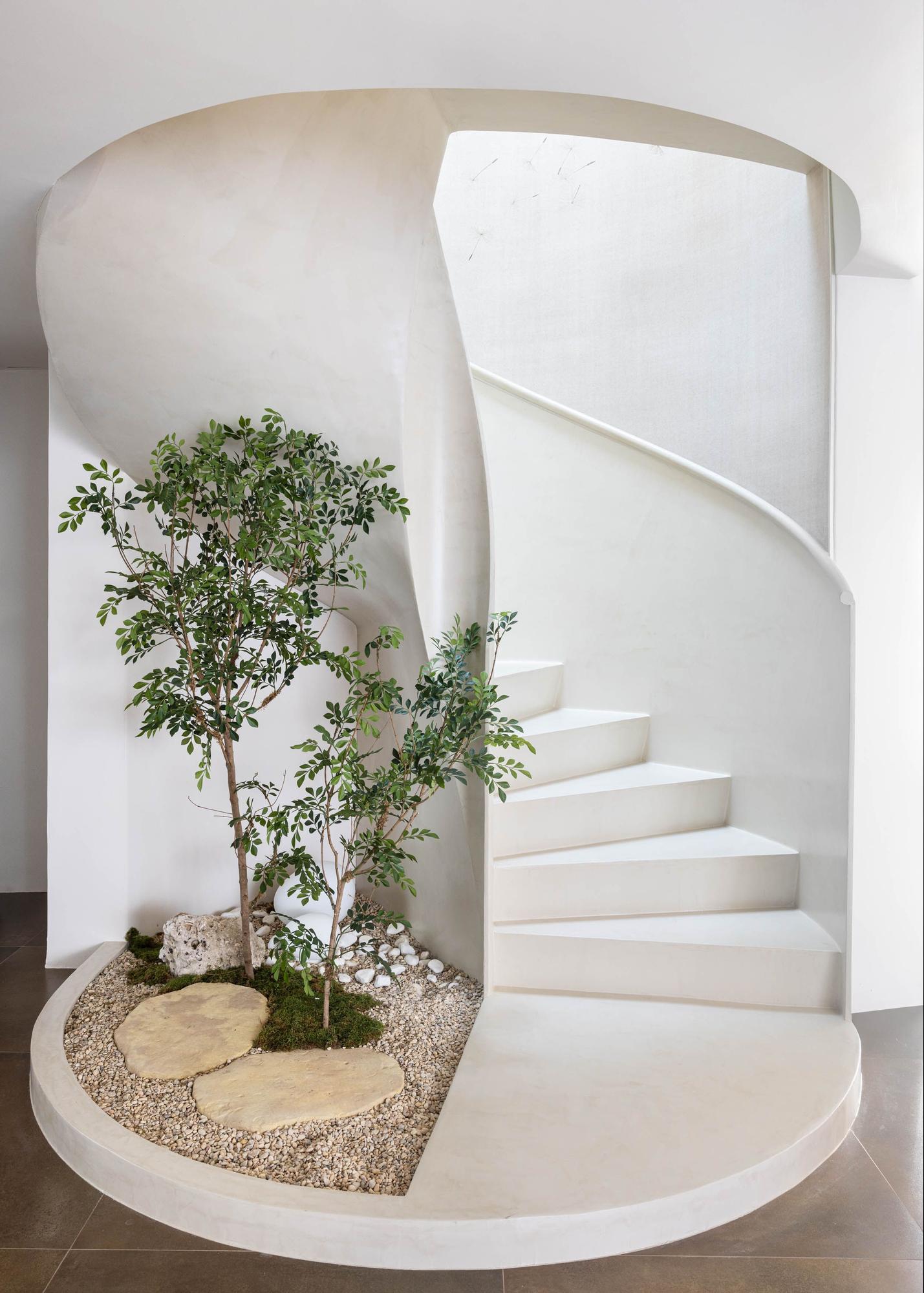 Pequeño jardín interior como este que combina piedras decorativas, dos ficus artificiales y una base de musgo, también artificial.