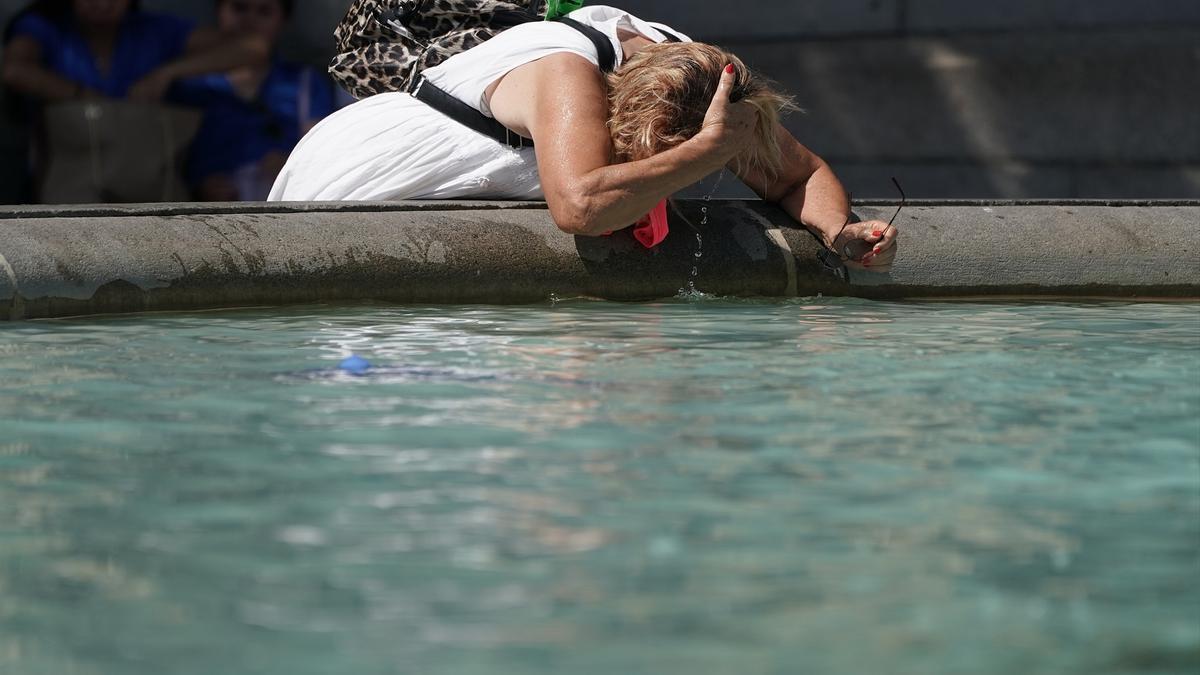 Una mujer se refresca en una fuente.