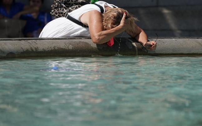Una mujer se refresca en una fuente.