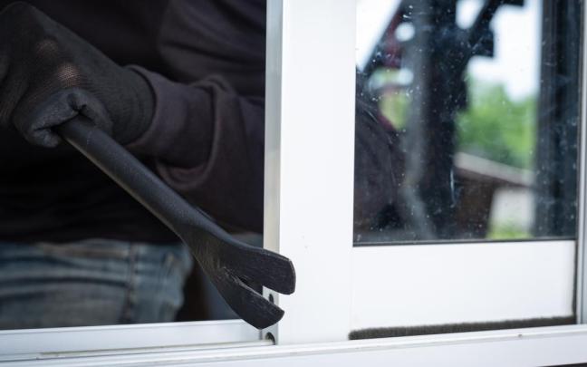 Imagen de archivo de un ladrón robando una ventana.