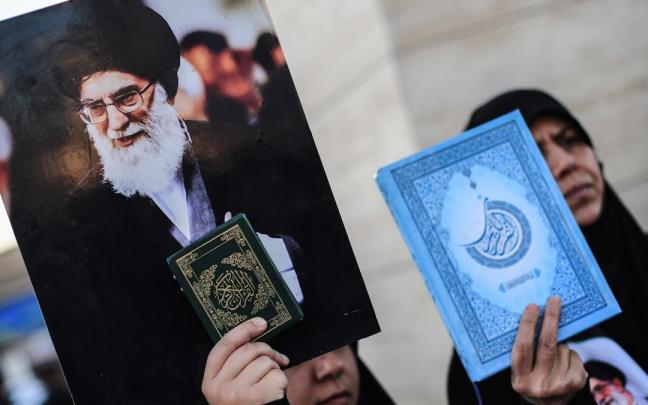 Dos mujeres en Irak sostienen sendas copias del Corán y una imagen del líder supremo de Irán, Ali Jameneí.