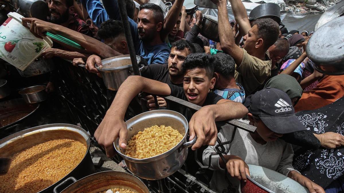 Los gazatíes hacen cola para conseguir comida en un campamento de refugiados en Jabalia.