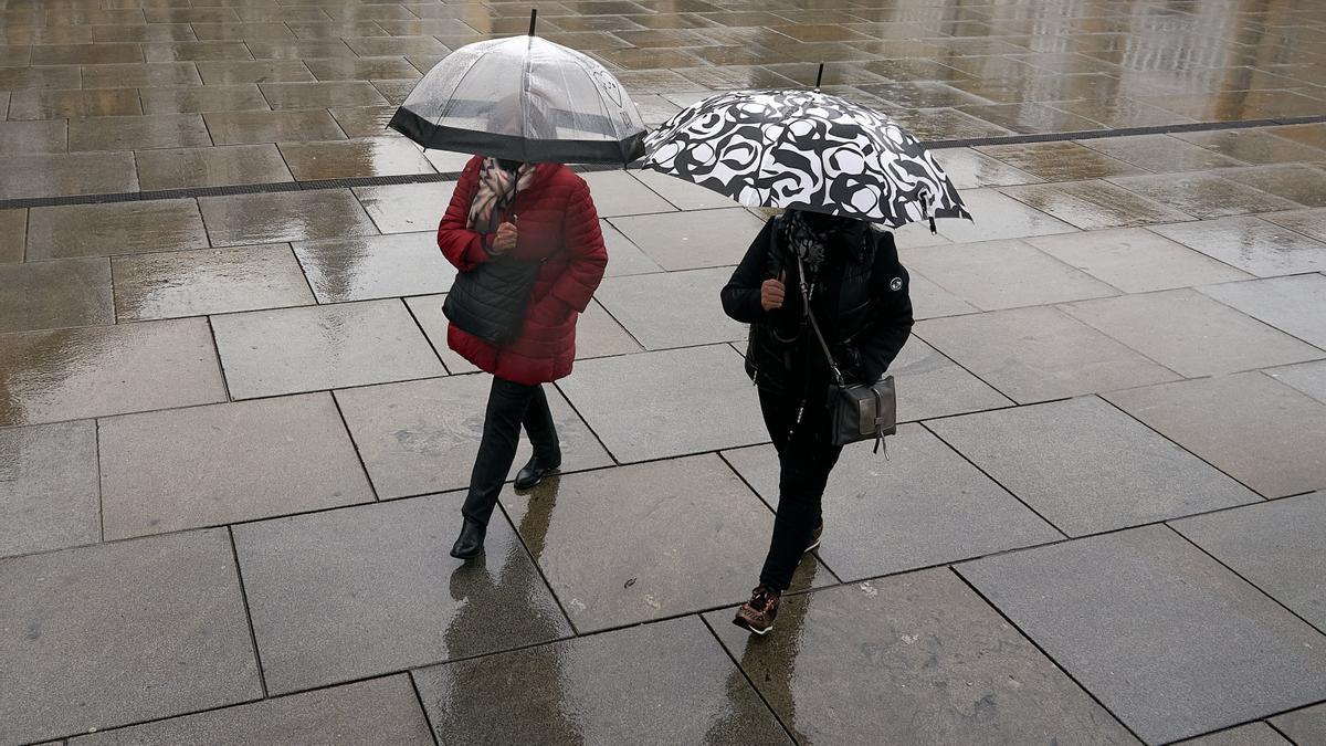 Dos personas se refugian con un paraguas de la lluvia en Vitoria-Gasteiz.