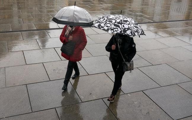 Dos personas se refugian con un paraguas de la lluvia en Vitoria-Gasteiz.