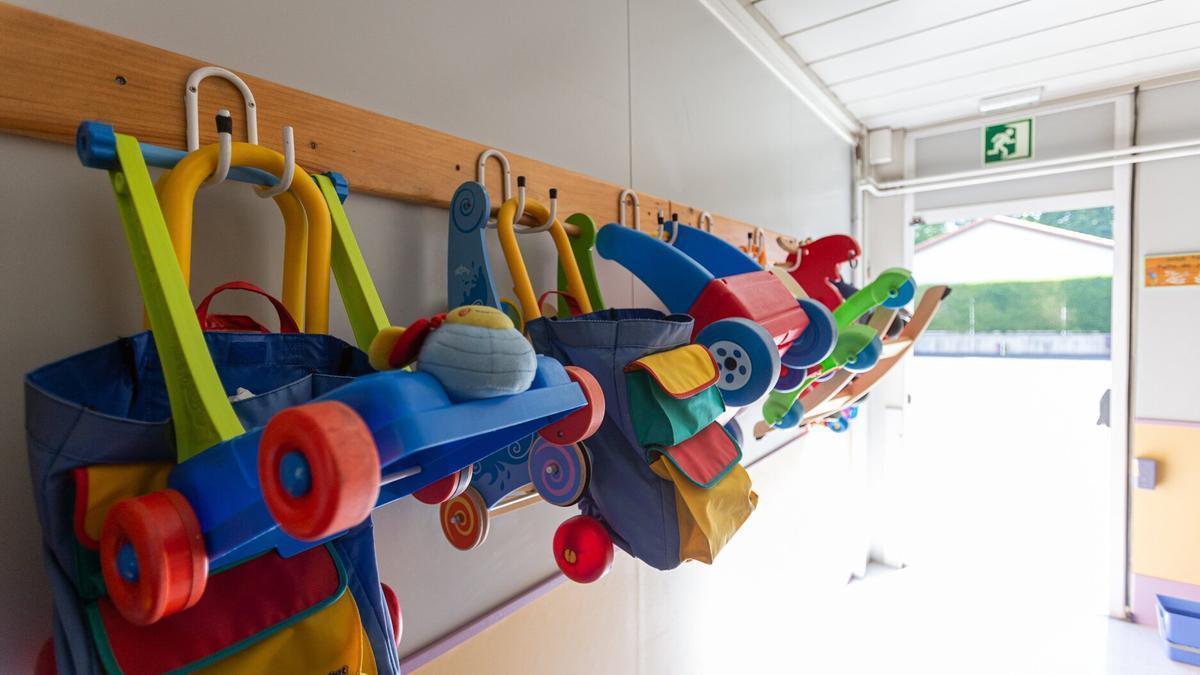 Varias mochilas colgadas de unos percheros en un centro escolar.