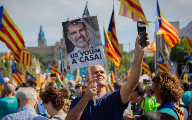 Un hombre sujeta un cartel con la foto del preso del Procés y Presidente de Òmnium Cultural, Joredi Cuixart, en la que se lee `Us Volem,a casa´(os queremos en casa) junto con banderas de la estelada.