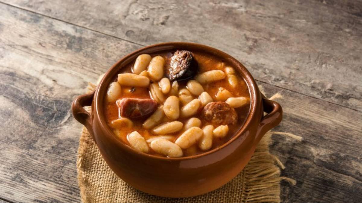 Alubias con chorizo y morcilla en una cazuela de barro.
