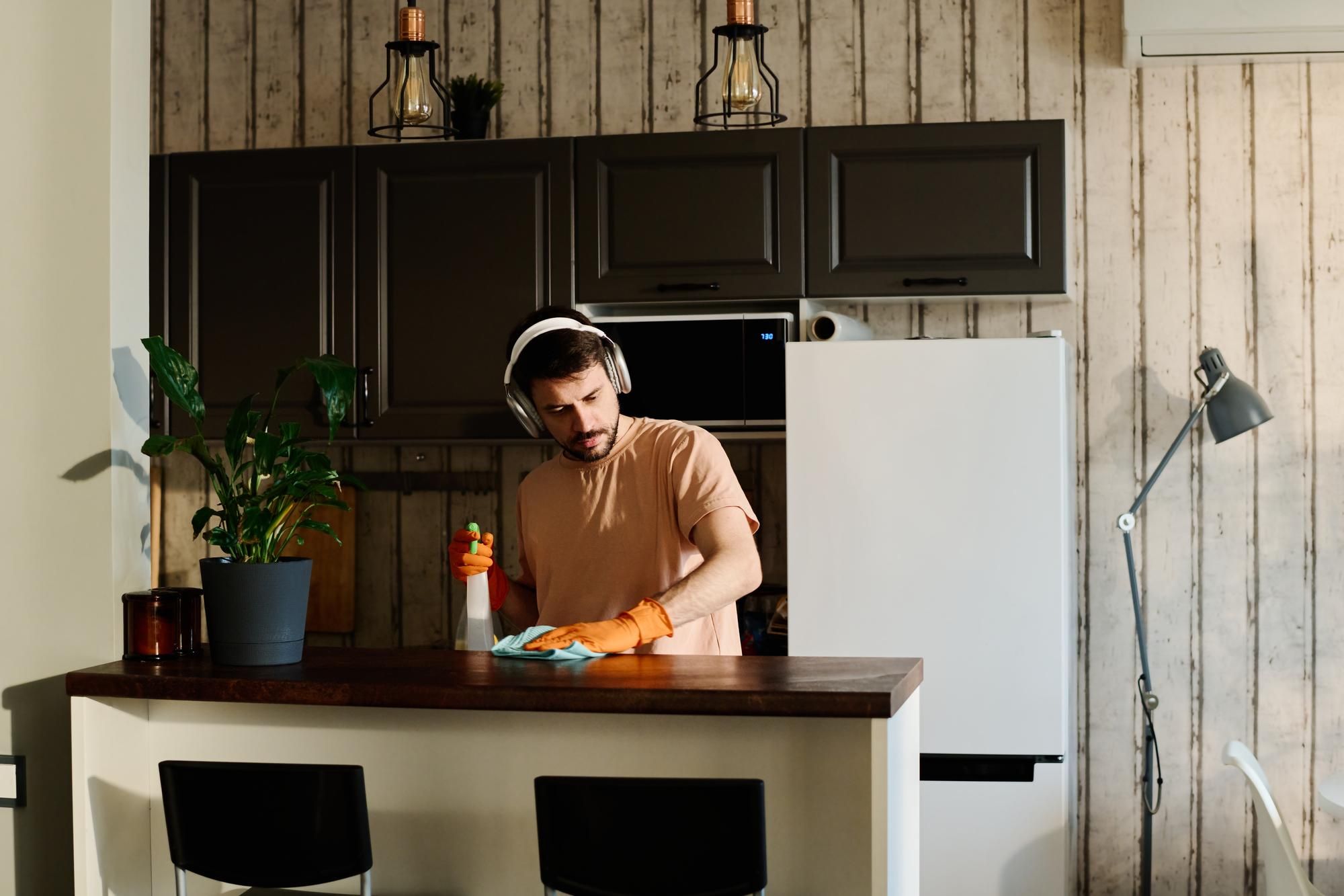 Un hombre limpia la cocina mientras escucha música.