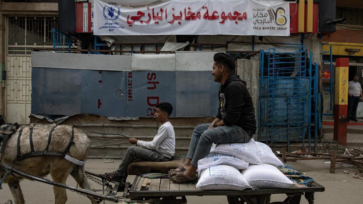 Palestinos cruzan ante una panadería cerrada en Ciudad de Gaza.