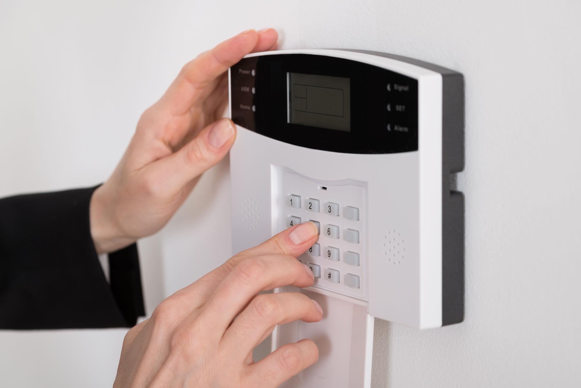 Primer plano de la mano de una mujer conectando la alarma antes de salir de casa.