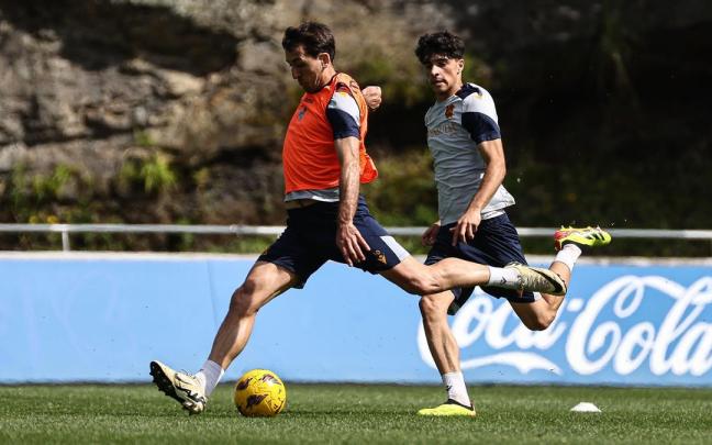 Mikel Oyarzabal ensaya un disparo ante la presión de Jon Martín hoy en Zubieta. / R.S.