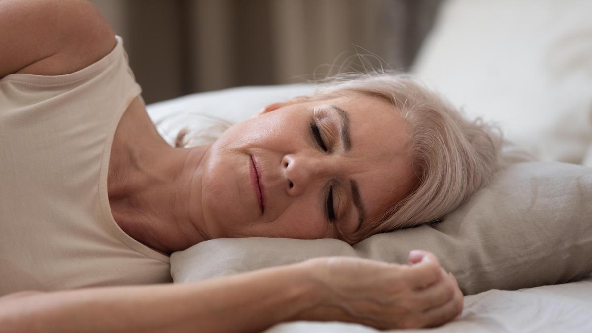 Señora duerme plácidamente en su cama.